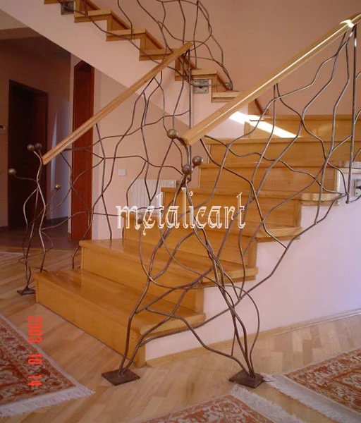 Balustradă cu linii ramificate, ca vrejurile, alături de scara de lemn deschis.