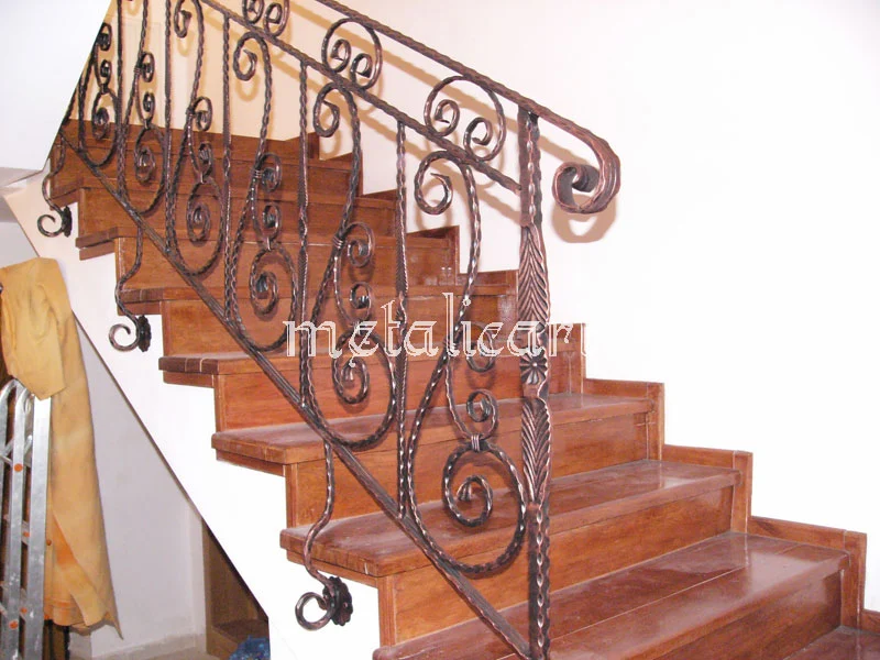 Balustradă cu volute mari succesive și mână curentă răsucită, de-a lungul scării de lemn.