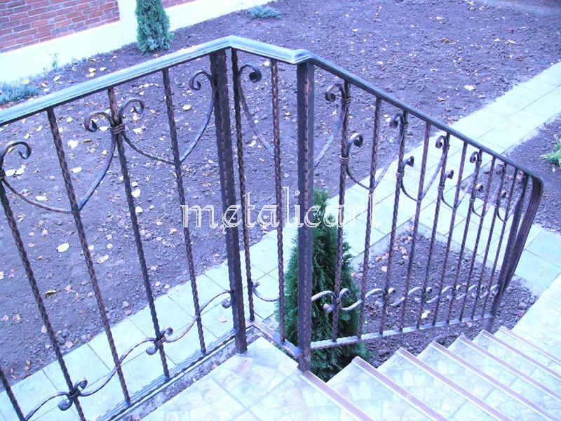 Balustradă exterioară cu bare răsucite și volute, mărginind o scară de acces în curte.