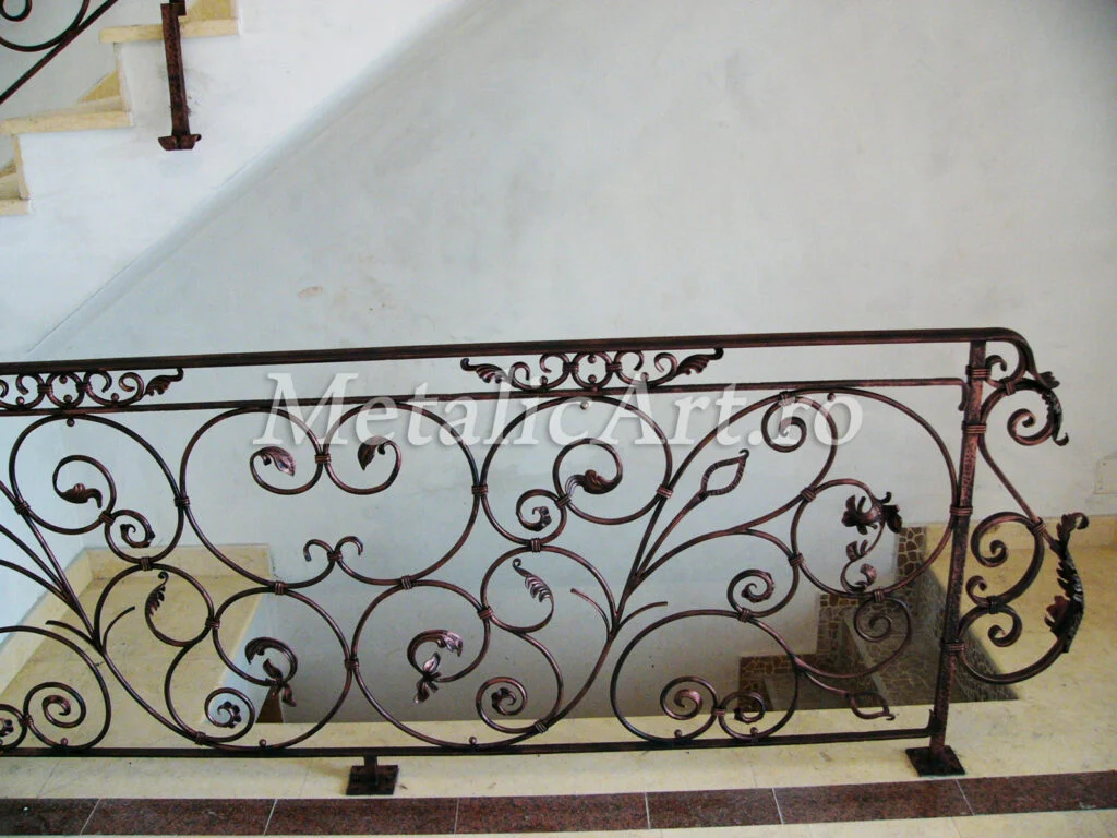 Balustradă cu volute dense, frunze și boboci, în finisaj brun-închis, montată pe podest de piatră.