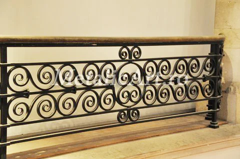 Balustradă cu două registre de volute mărunte, sub mână curentă din lemn.