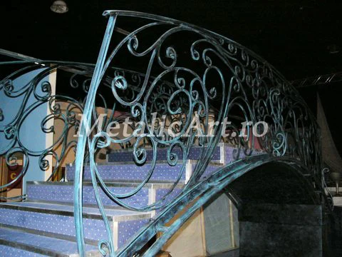 Balustradă curbată de scară, cu volute dese și finisaj verzui-patinat.