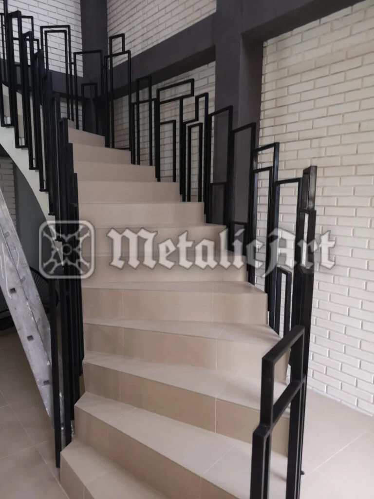 Balustradă modernă din bare drepte, în trepte, pe scară cu perete de cărămidă albă.