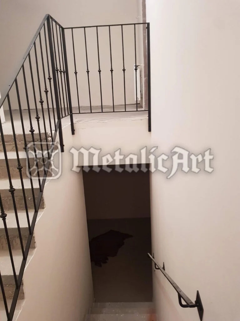 Balustradă simplă de scară și palier, cu bare verticale și noduri torsionate.