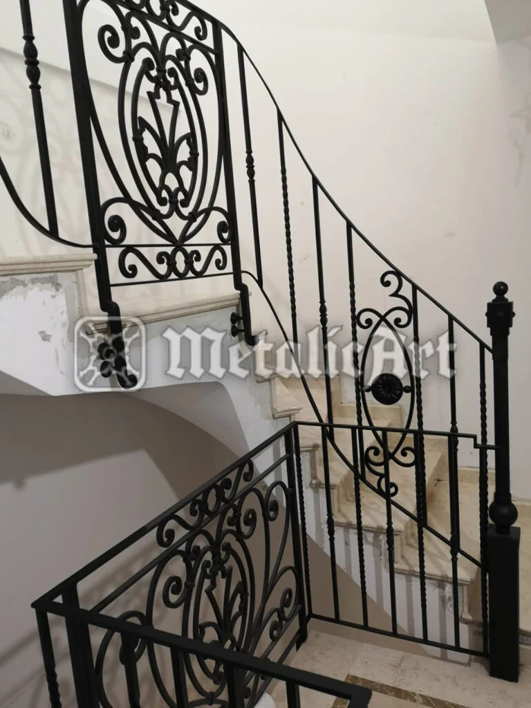 Balustradă neagră de scară și palier, cu bare torsionate și panou ornamental central.