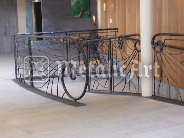 Balustradă de palier curbată, cu bare verticale și volute laterale, într-un interior modern.