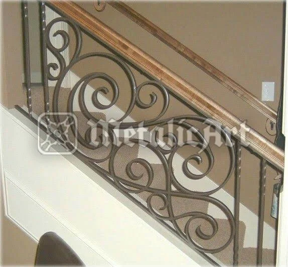Balustradă de scară cu volute rotunde repetate, sub mână curentă din lemn deschis la culoare.