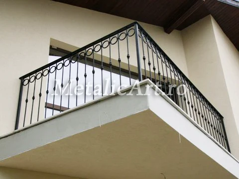 Balustradă de balcon cu volute mărunte și noduri forjate, urmând colțul casei.