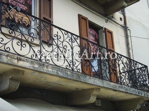 Balustradă de balcon cu volute dese, pe o clădire cu console de piatră.