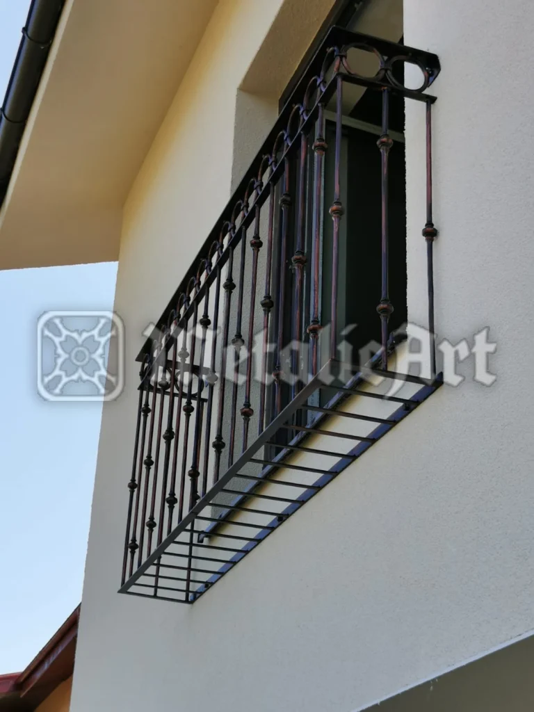 Balustradă de balcon francez cu bare verticale, noduri forjate și registru orizontal la bază.