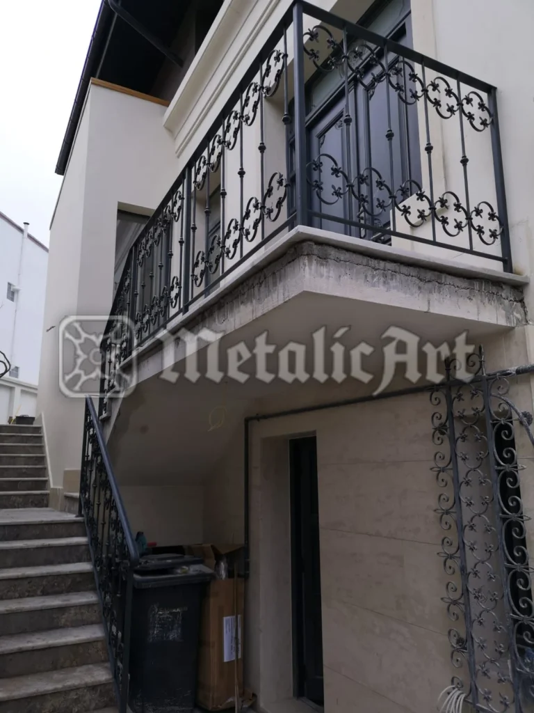 Balustradă de balcon cu bare verticale și panouri decorate cu crini.