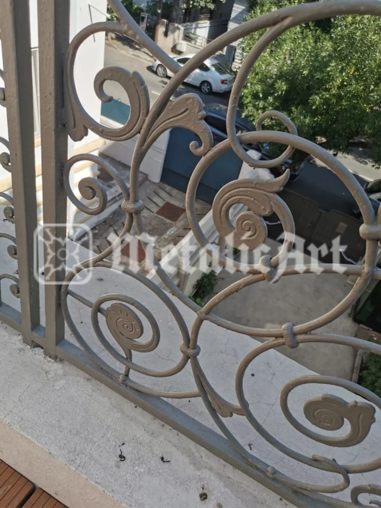 Detaliu de balustradă de balcon, cu volute, frunze și medalioane, în finisaj deschis.