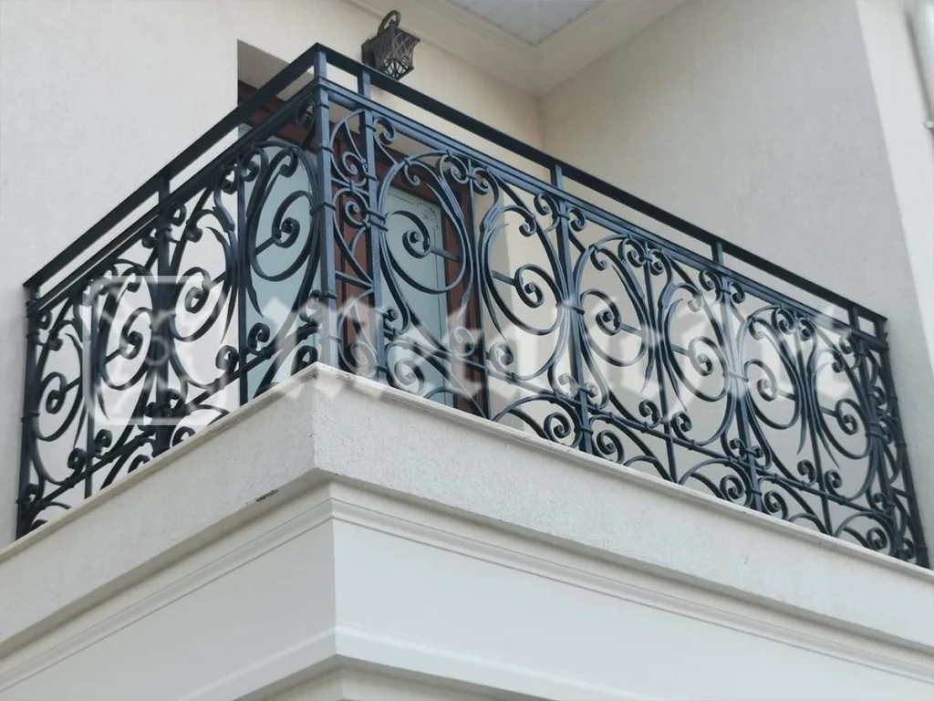 Balustradă de balcon cu desen bogat de volute, la o casă cu cornișă profilată.