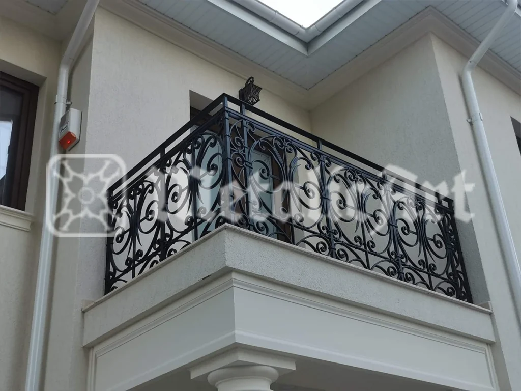 Balustradă de balcon cu volute dese, urmând colțul unei case albe.