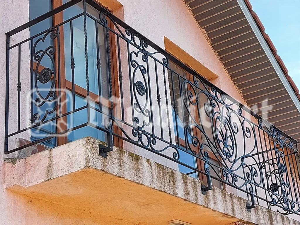 Balustradă de balcon cu volute și rozete, pe o fațadă portocalie.