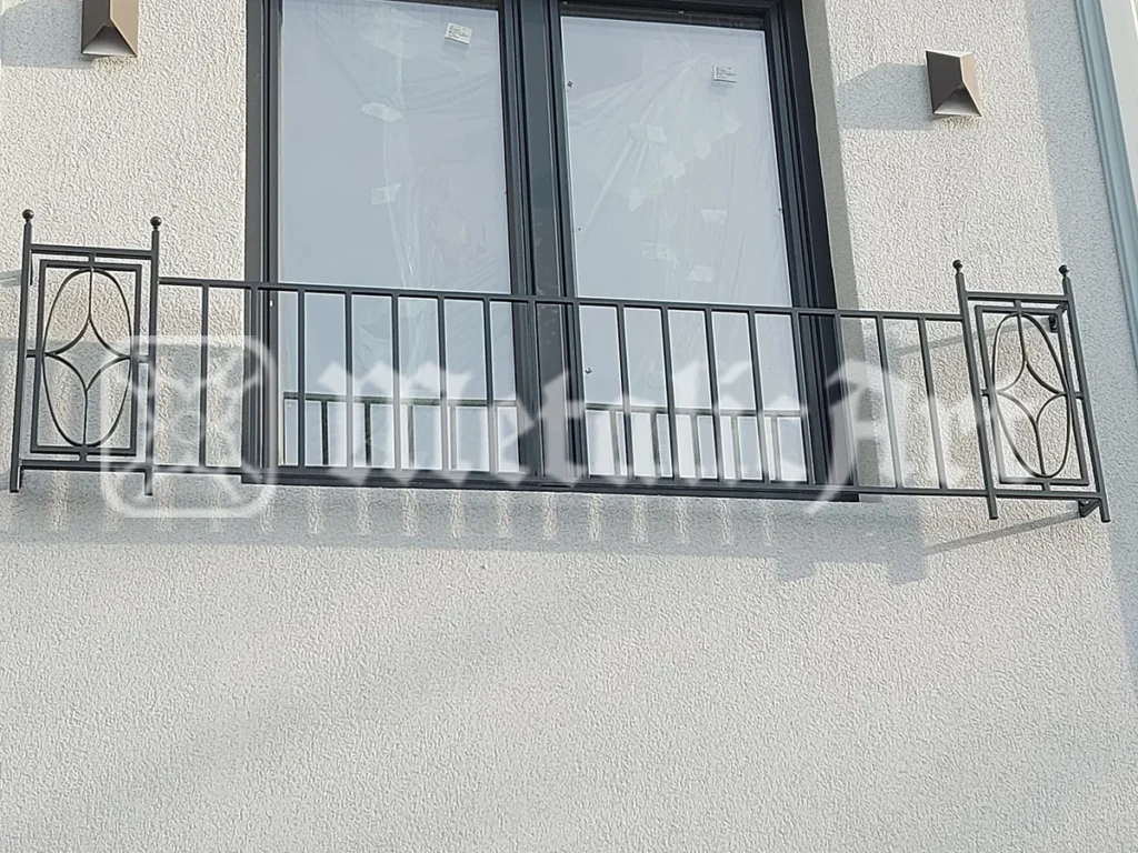 Balustradă de balcon cu bare verticale și medalioane ovale la capete.
