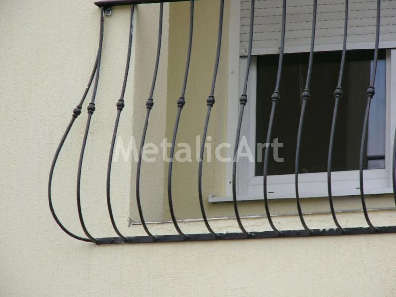 Grilaj cu bare curbate și noduri forjate, urmând un colț de fațadă.