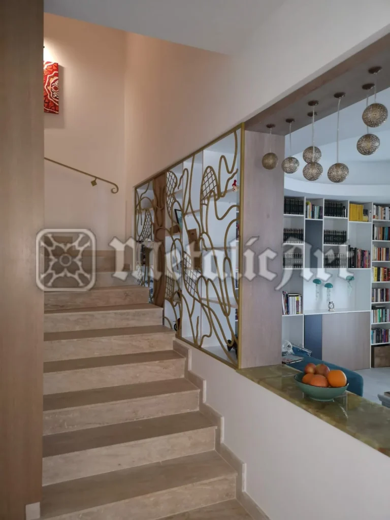 Panou decorativ cu desen liber forjat, separând scara de zona de living.