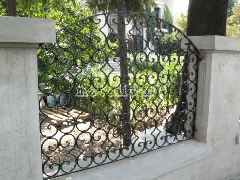 Panoul de gard cu volute mărunte, pe soclul de beton.