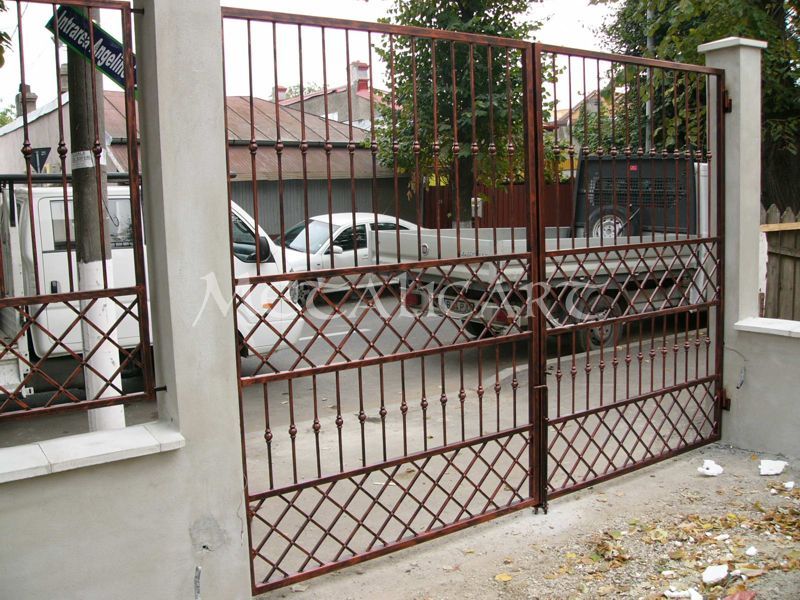 Poartă auto cu bare verticale și panou romboidal la bază, în finisaj ruginiu.