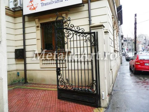 Poartă auto cu volute, la intrarea unei clădiri de birouri.