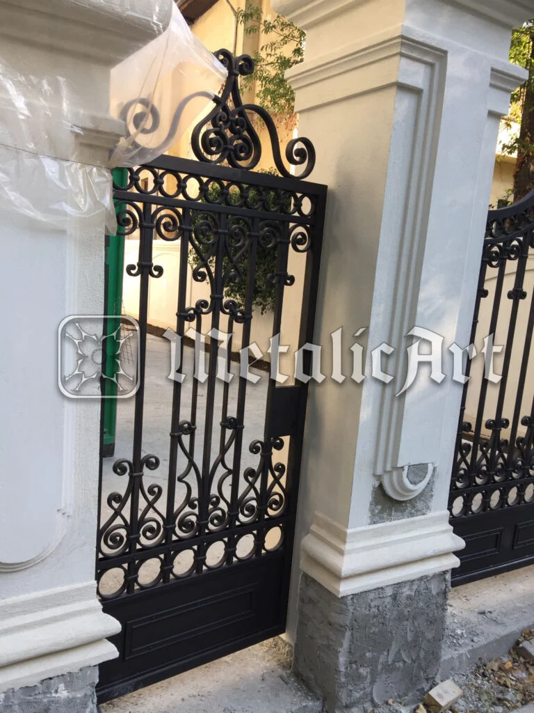 Poartă pietonală înaltă, cu volute și cercuri, între stâlpi cu profile clasice.