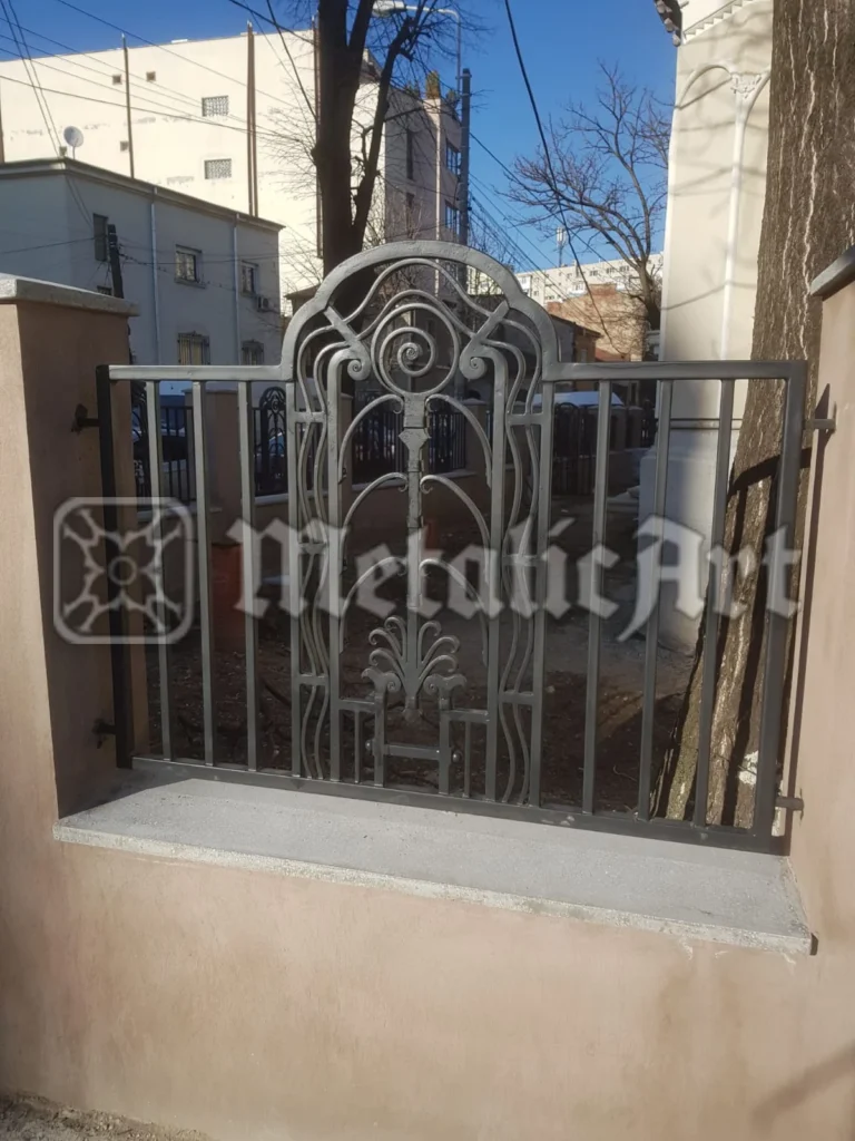 Panou de gard cu medalion central decorat cu volute și motiv floral.