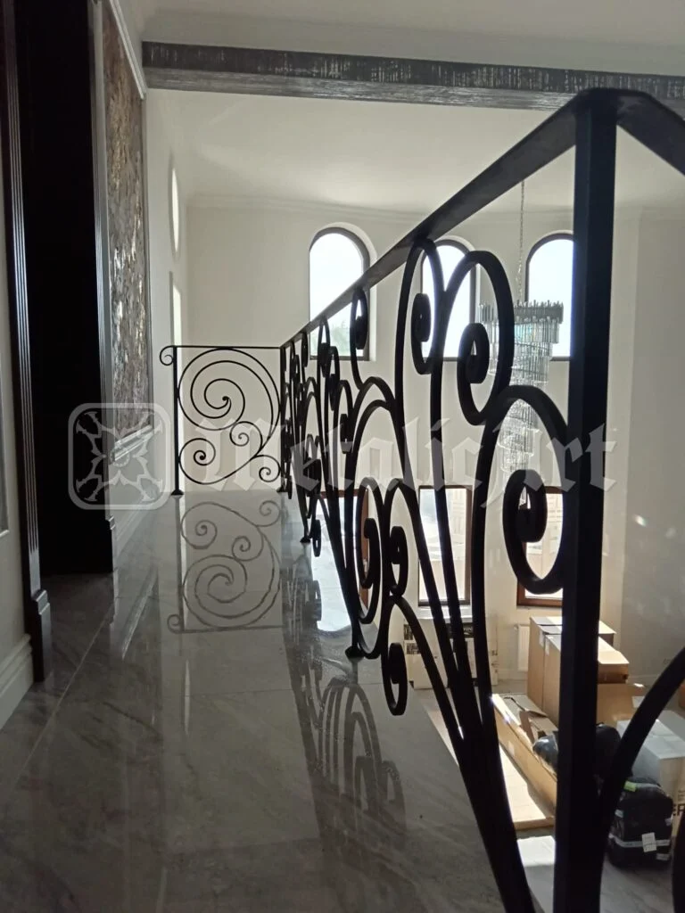 Coridorul de la etaj, văzut prin volutele balustradei.