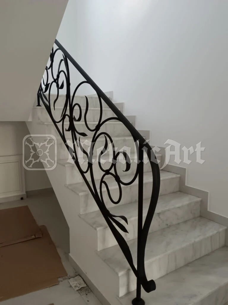 Panoul de la capătul scării cu trepte de marmură, cu volute mari prinse în cadru.