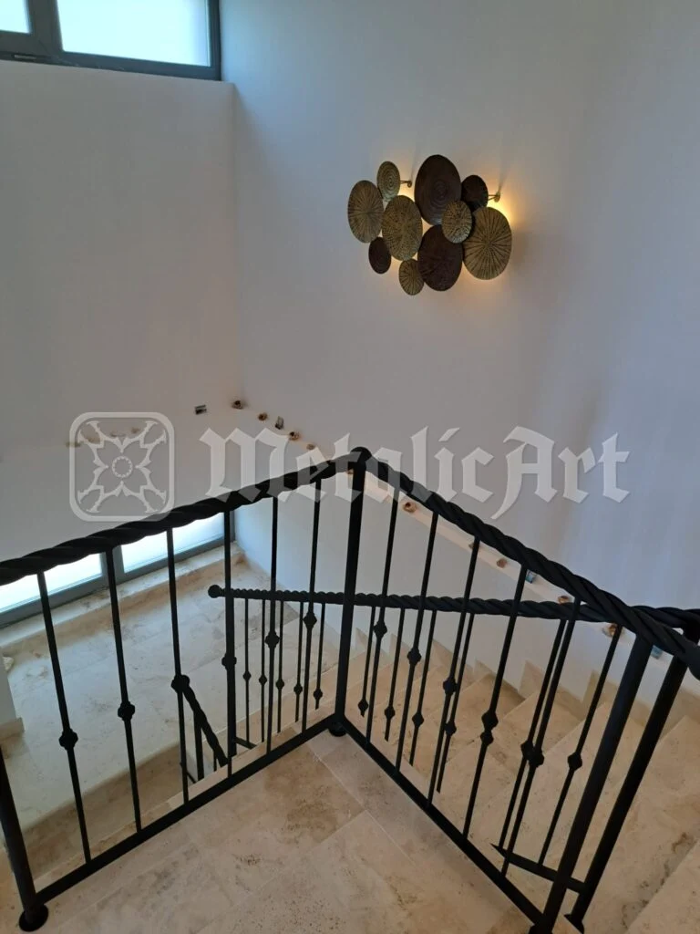 Casa scării văzută de sus, peste balustradă, cu aplica rotundă pe perete.