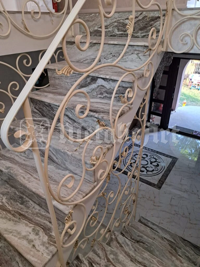 Balustrada de lângă intrare, cu mozaicul din podea și ușa deschisă.