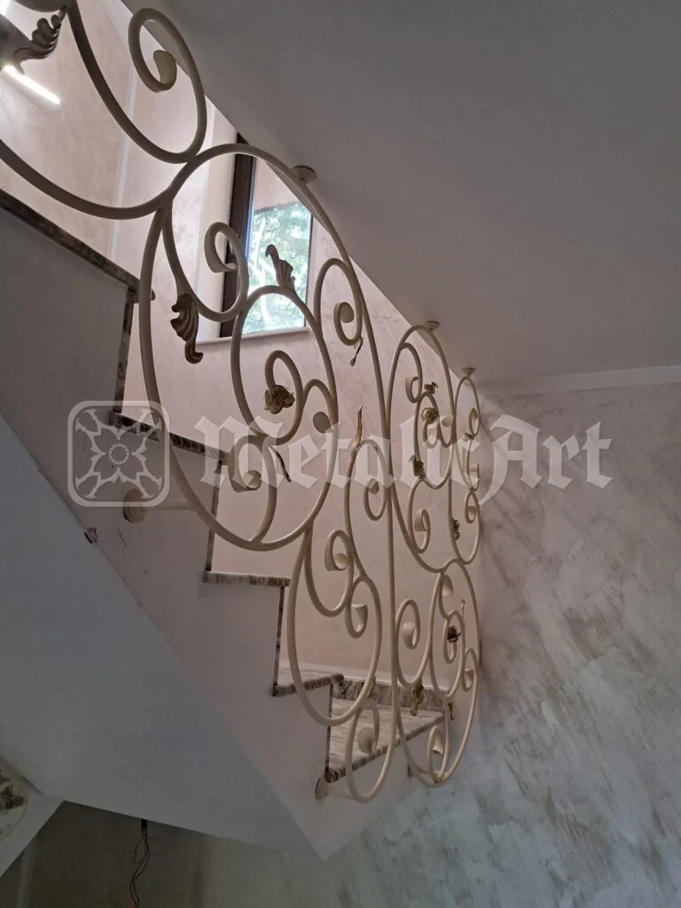 Balustrada văzută de jos, cu volutele pe fundalul tavanului alb.