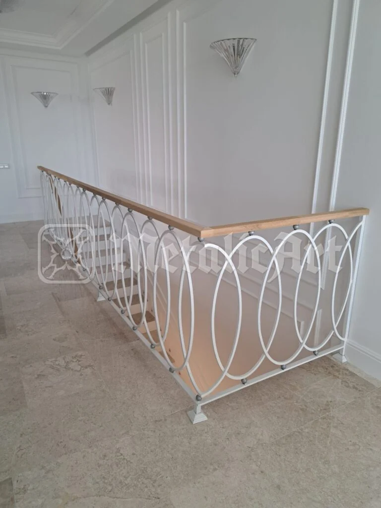 Balustrada golului de scară, cu cercuri întrepătrunse și mână curentă de lemn.