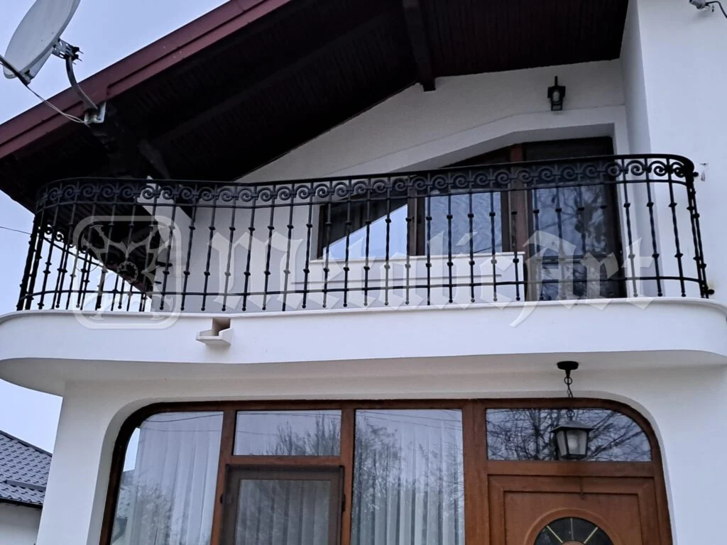 Balustrada balconului văzută dinspre intrare, cu ușa de lemn dedesubt.