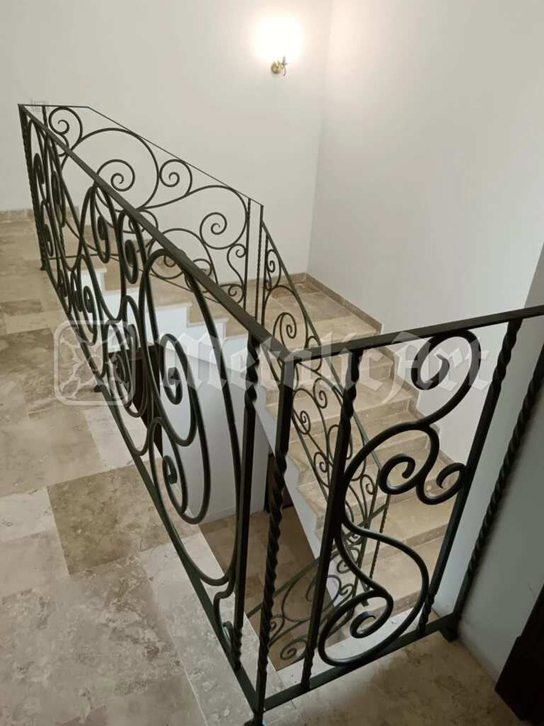 Panoul balustradei de pe podest, cu volute prinse în cadru și bare torsadate.