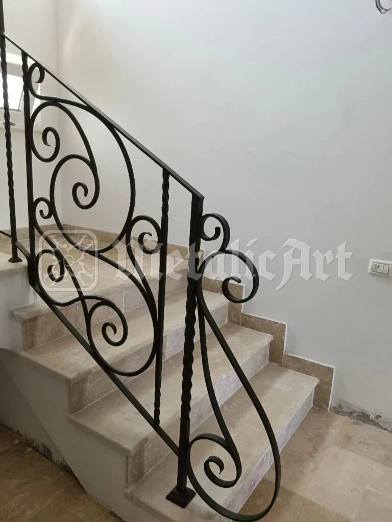 Rampa scării văzută dinspre hol, cu volutele desenate pe peretele alb.