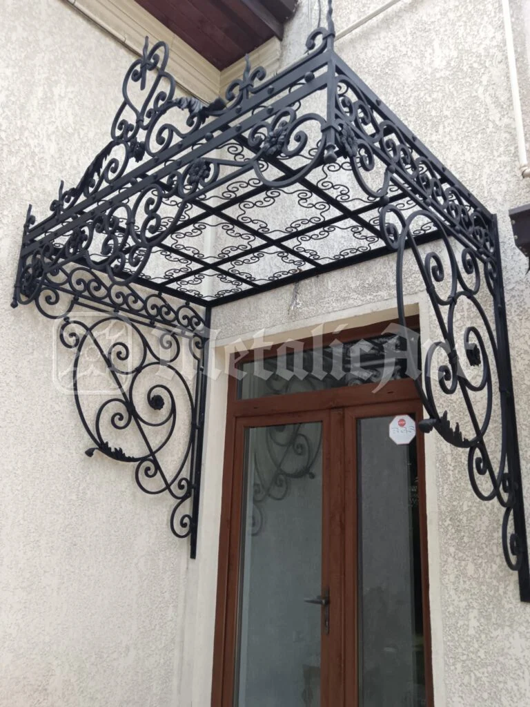 Copertina în două ape deasupra ușii, cu console de volute.