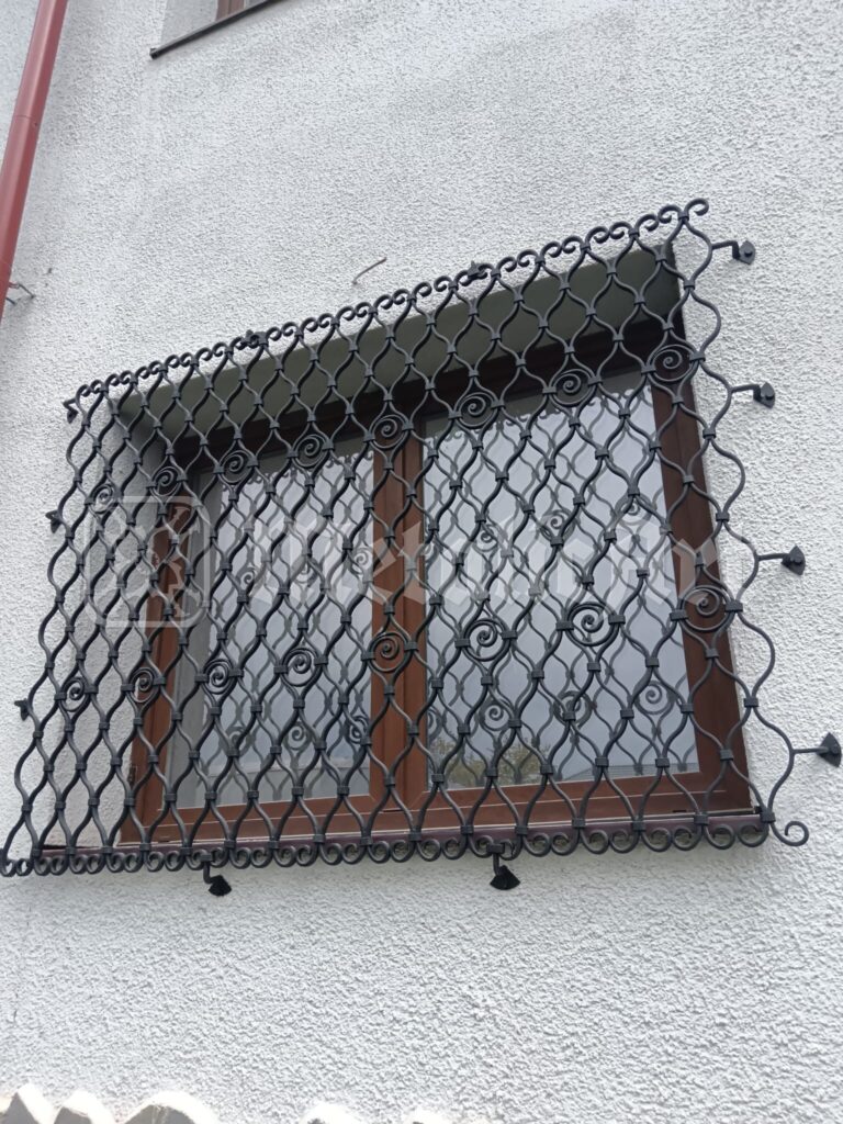 Grilaj cu împletitură de ochiuri, montat în afara ferestrei de lemn.