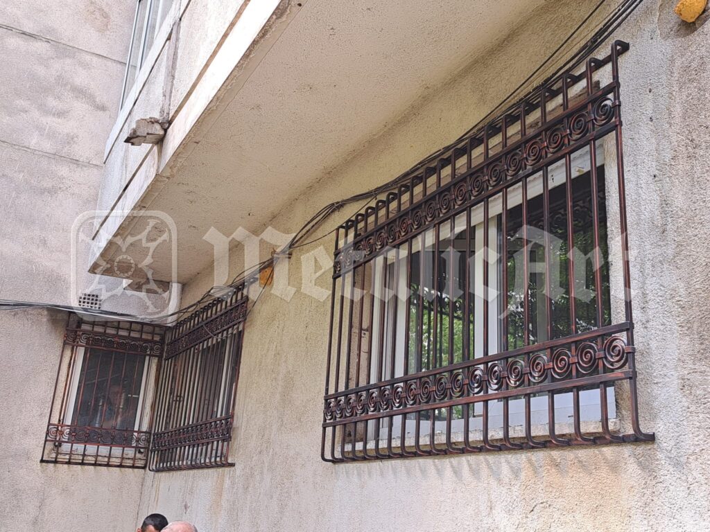 Grilajele celor două ferestre vecine, sub cornișa clădirii.