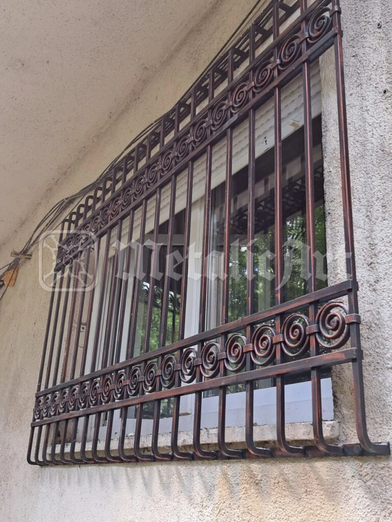 Grilaj de fereastră cu volute pe brâu, văzut din stradă.