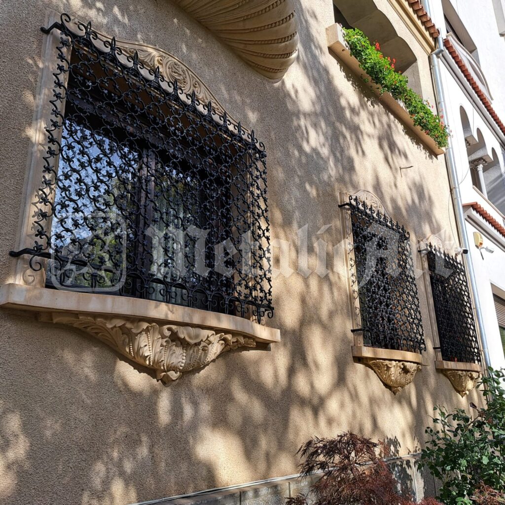 Grilajele a două ferestre vecine, pe fațada casei.