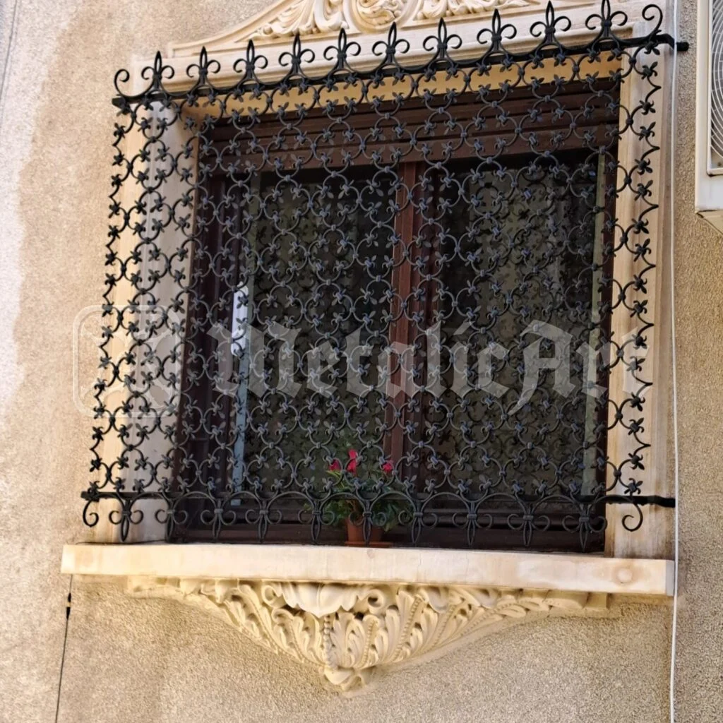 Grilaj ornamental la fereastra cu ancadrament de piatră, văzut din față.