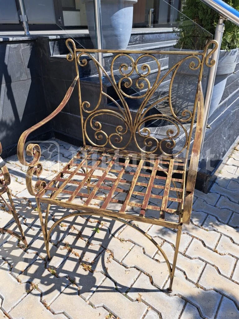 Fotoliul cu brațe răsucite, lângă peretele de marmură.