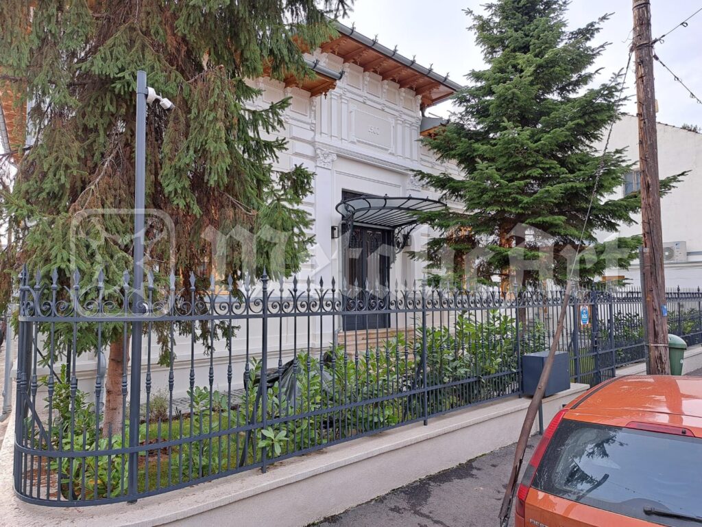 Gardul de-a lungul trotuarului, cu casa în spate.