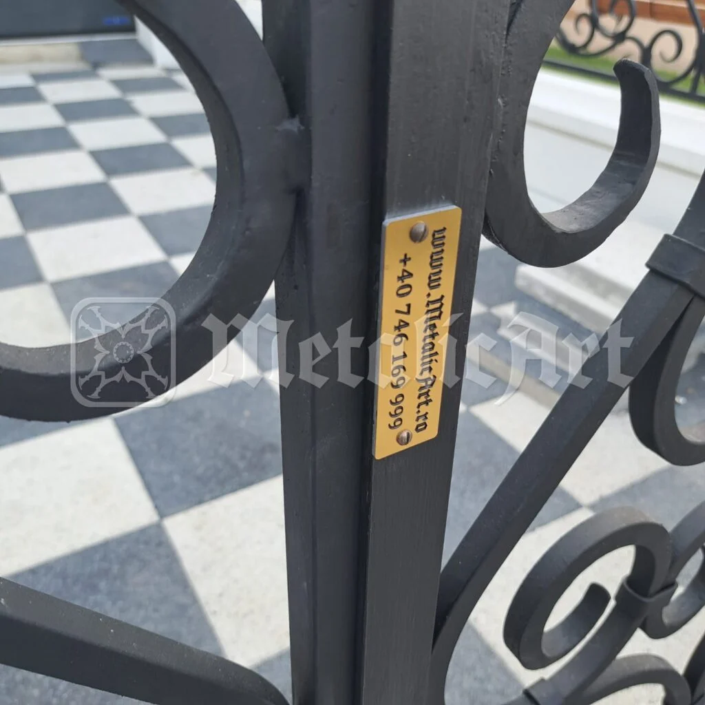 Plăcuța de alamă MetalicArt, prinsă pe bara porții.