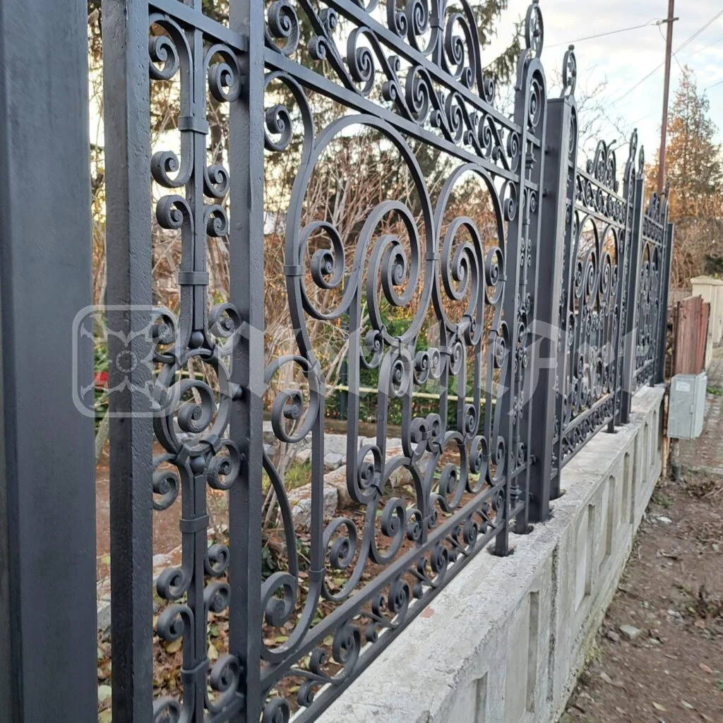 Panoul de gard văzut din curte, cu volutele pe toată lățimea.