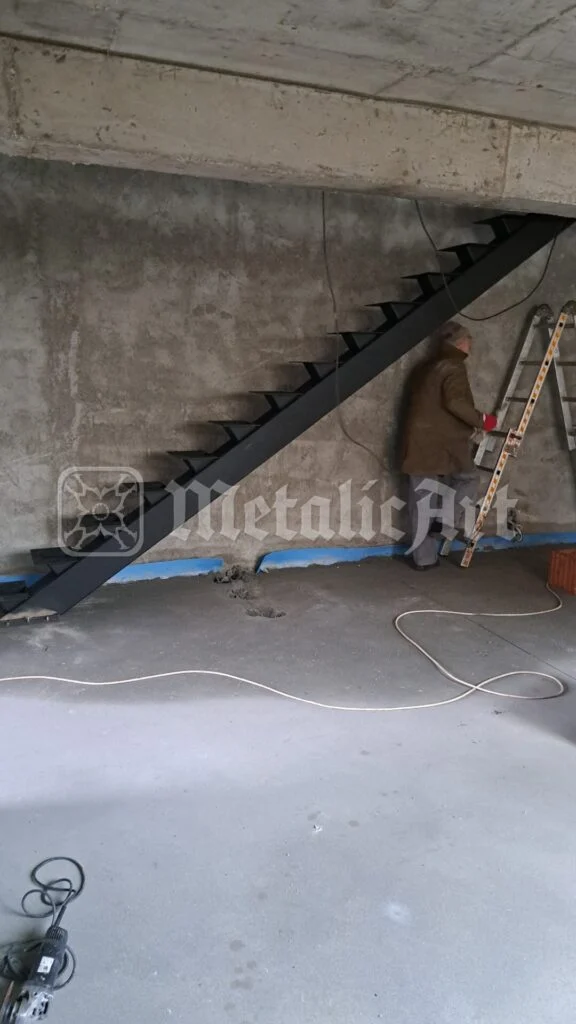 Scara văzută din lateral, cu un om lucrând în spate.