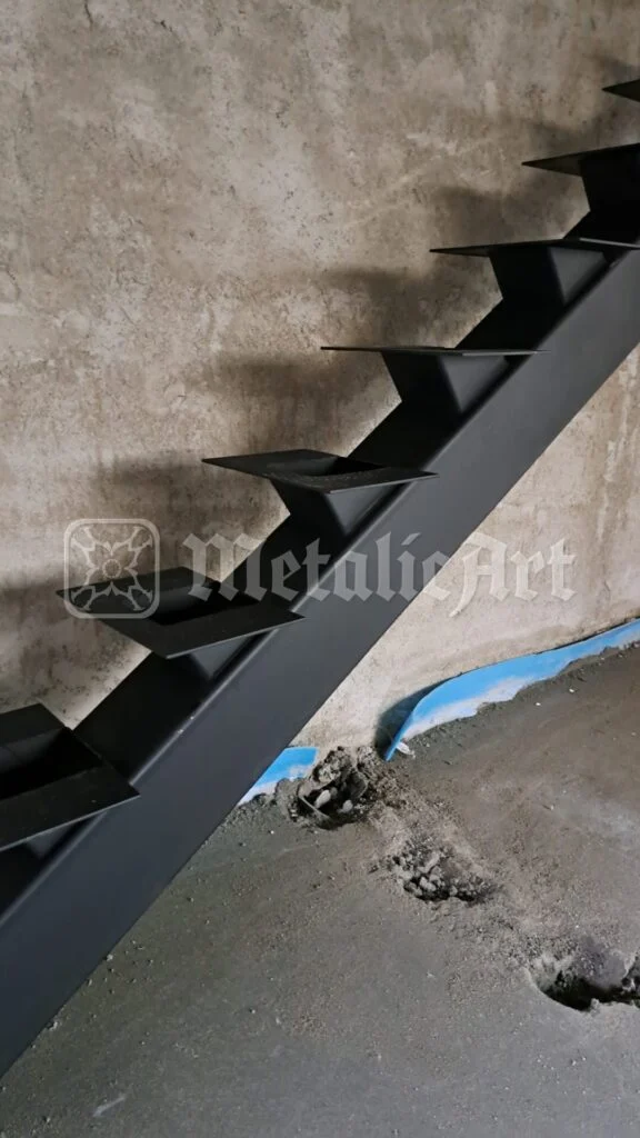 Scara metalică cu vang central, montată în structura de beton.