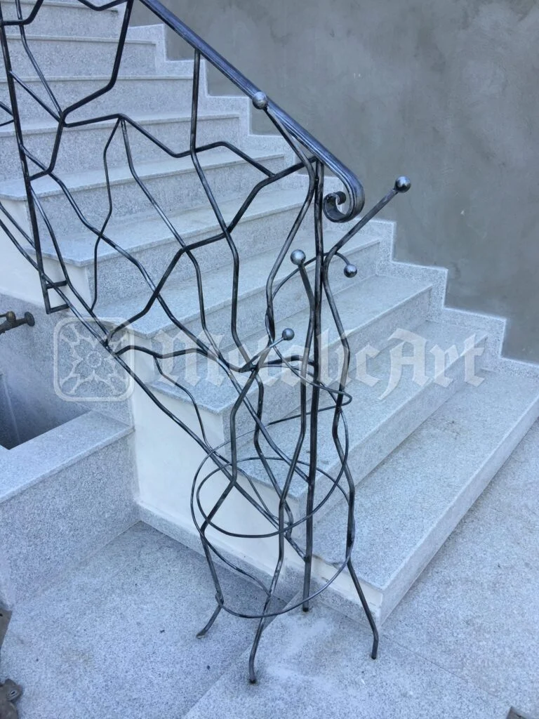 Balustradă cu desen neregulat, ca o rețea de ramuri, pe scară de piatră deschisă.