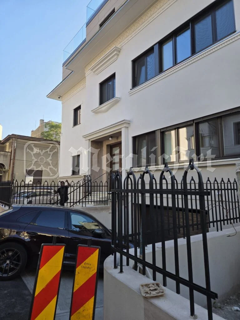 Casa și gardul din fier forjat, văzute de pe stradă.